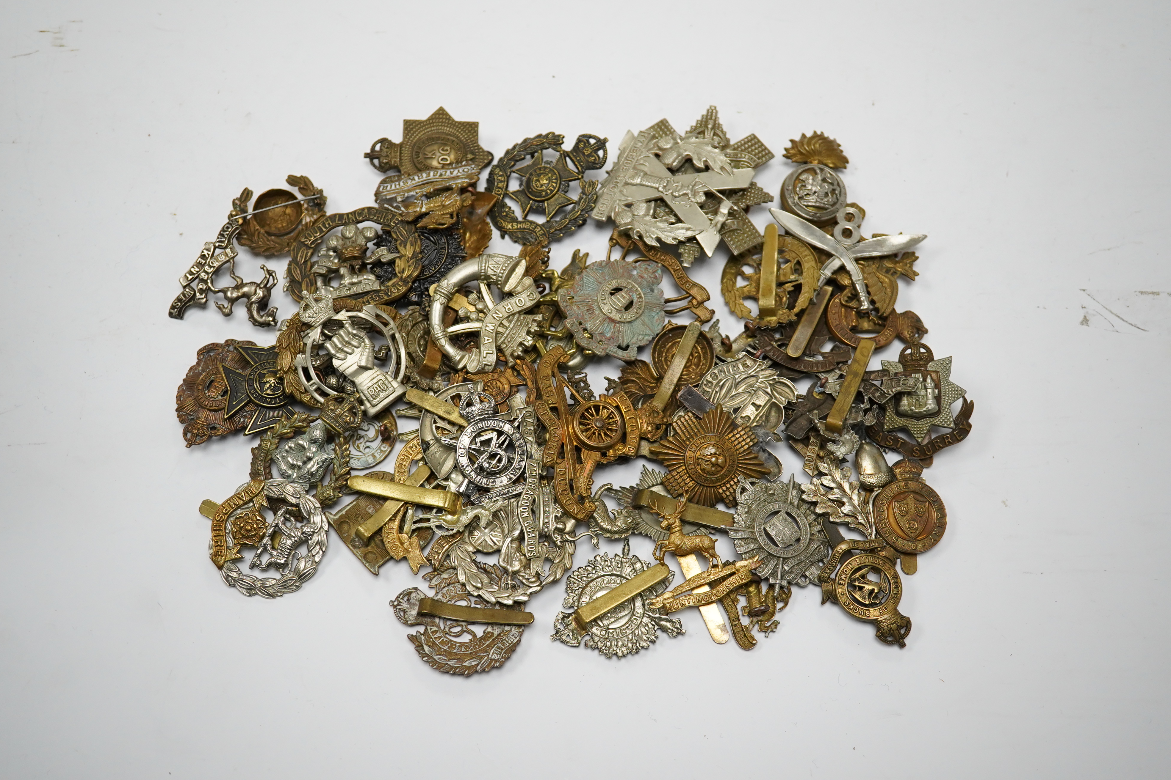 Sixty military cap badges, including; the Hampshire regiment, the South Lancashire Regiment, Prince of Wales Volunteers, the Tyneside Scottish Regiment, the Royal Artillery, the Norfolk Regiment, the Army Ordinance Corps